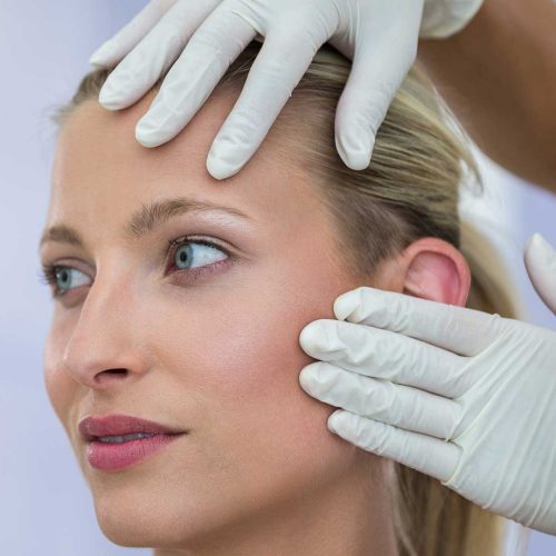 doctor-examining-female-patients-face-from-cosmetic-treatment